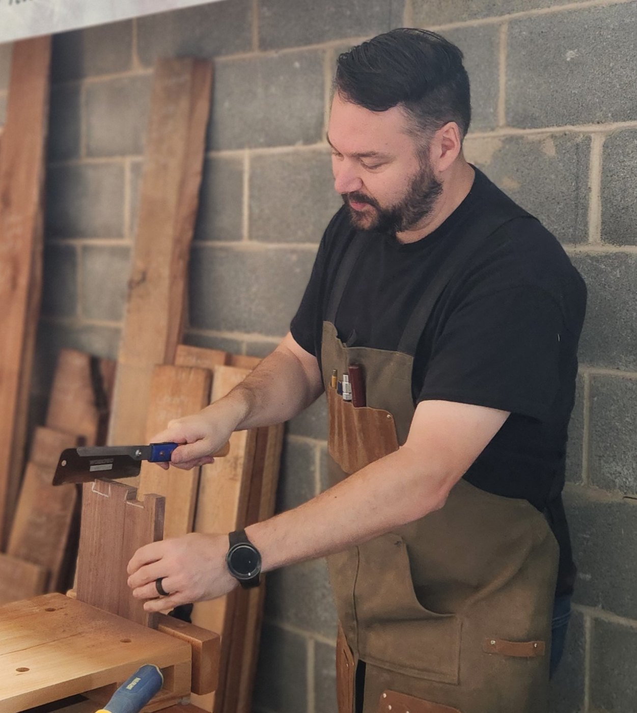 James Phillips cutting joinery by hand at a workbench.