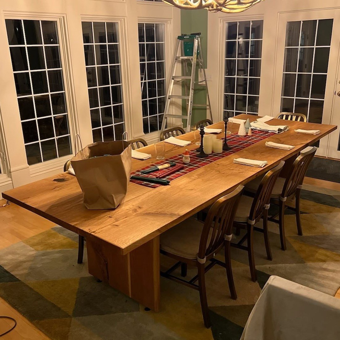 A long live-edge dining table set for dinner in a client&rsquo;s dining room.