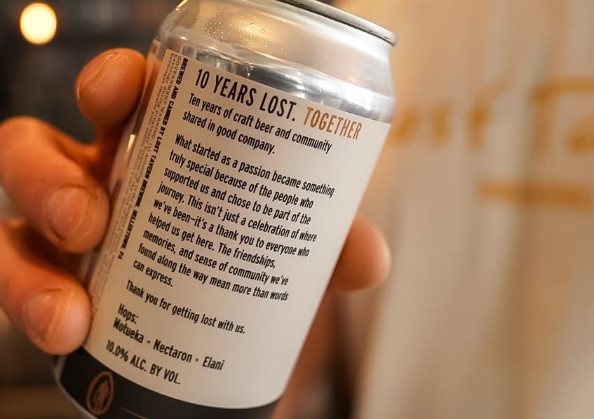 A hand holding the 10 Years Lost Triple IPA can, its back label reading 10 Years Lost. Together.