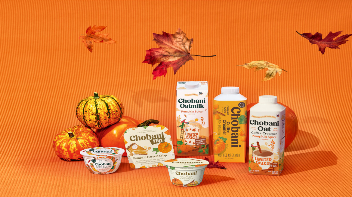 Chobani pumpkin spice products, including Greek yogurt, a Flip cup, oat milk and two coffee creamers, set among pumpkins and autumn leaves on an orange backdrop.