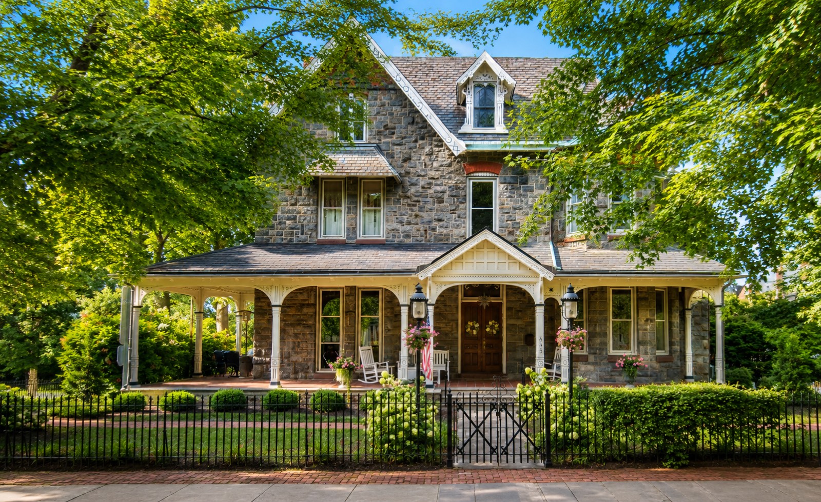 A Gothic Revival stone house with steep gables, sawn bargeboard trim and a deep wraparound porch