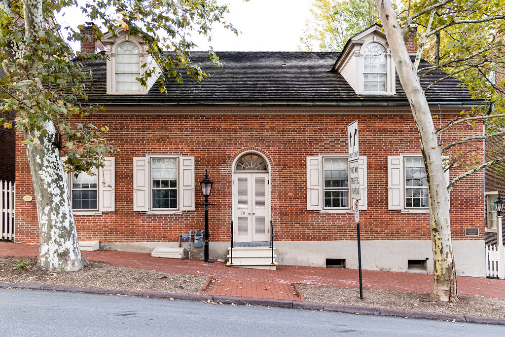 A modest one-and-a-half storey brick house with two arched dormers and a fanlight over the door