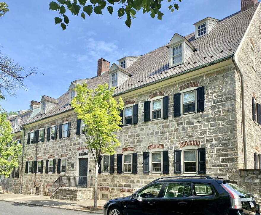 A long limestone Moravian building with brick jack-arched window heads and rows of dormers