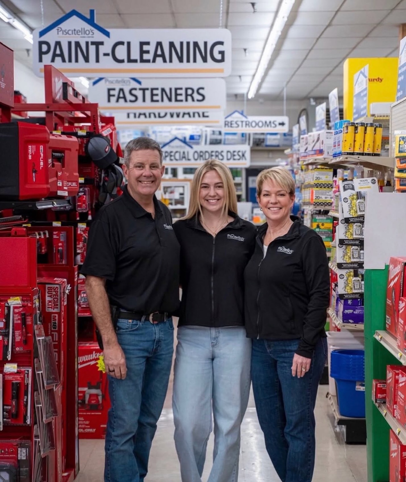 Dave and Lisa Colver standing with their daughter in a Piscitello's aisle beneath the Paint-Cleaning and Fasteners aisle signs.