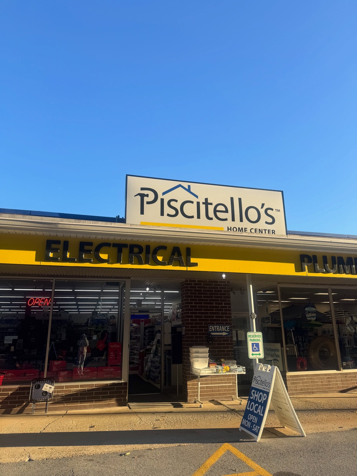 The Piscitello's Home Center storefront on Wood Avenue, with ELECTRICAL and PLUMBING lettering across a yellow awning and a Shop Local sidewalk sign by the entrance.