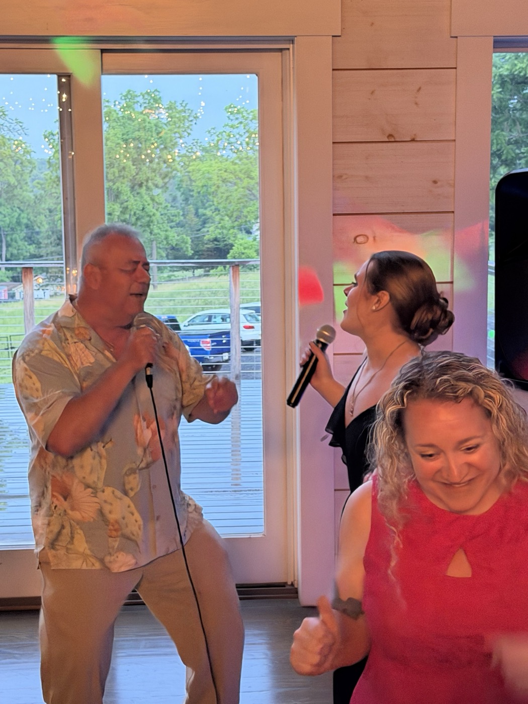 Ron Serafin singing into a microphone at a reception while a guest sings the other part beside him