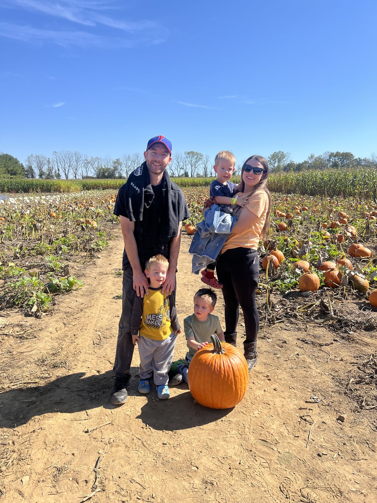 A family with three young children stands in the pick your own pumpkin patch