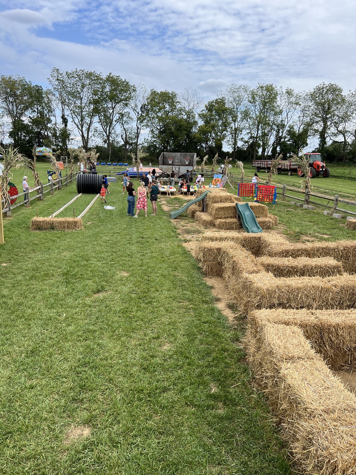 Families in the play area beside a straw bale maze, slides and giant lawn games